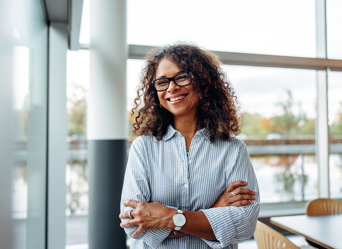 Business Insurance - Portrait of a Smiling Business Woman Standing in a Well Lighted Modern Office on a Sunny Day
